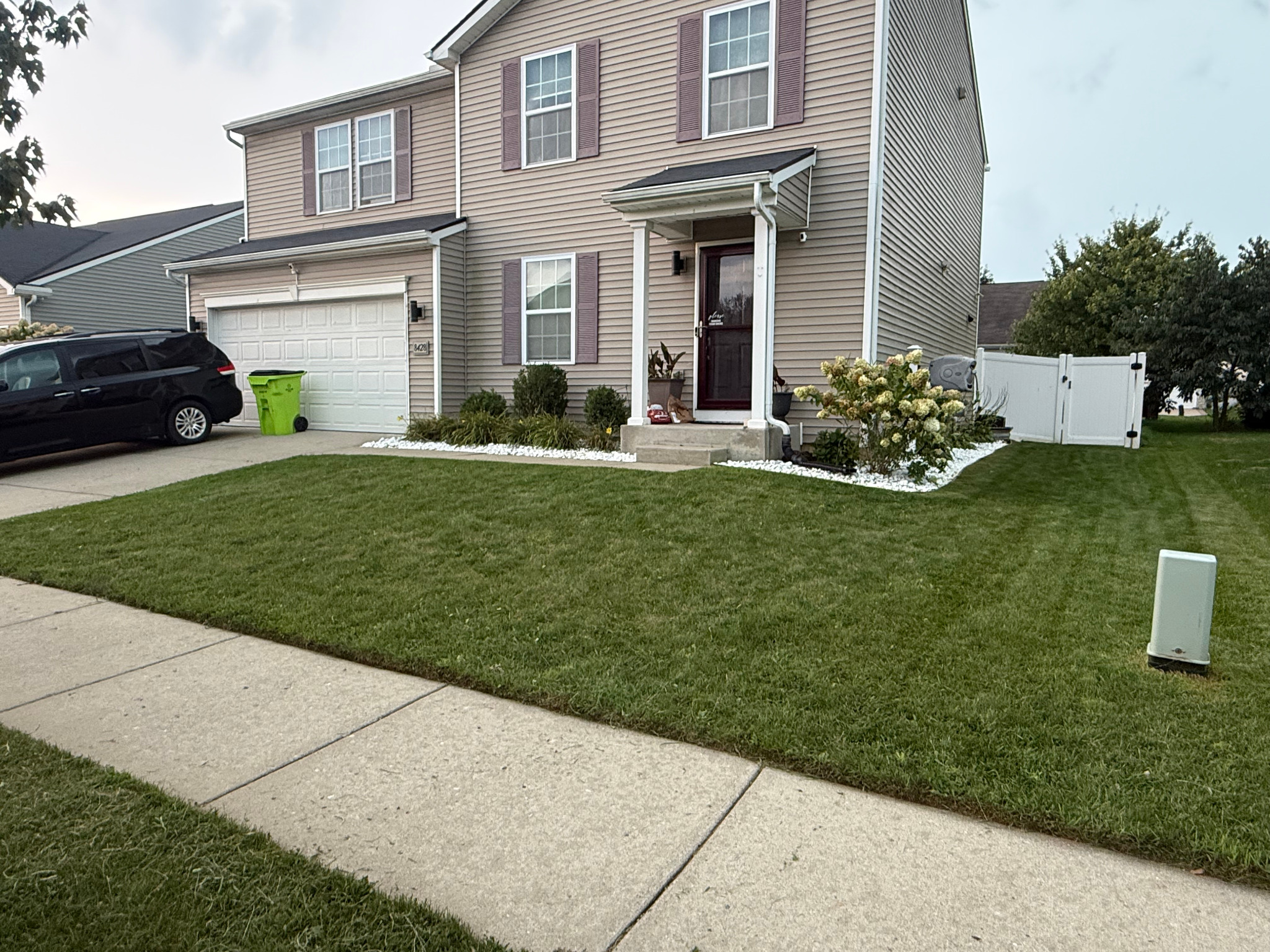 Completed lawn care at a home with white stone landscaping